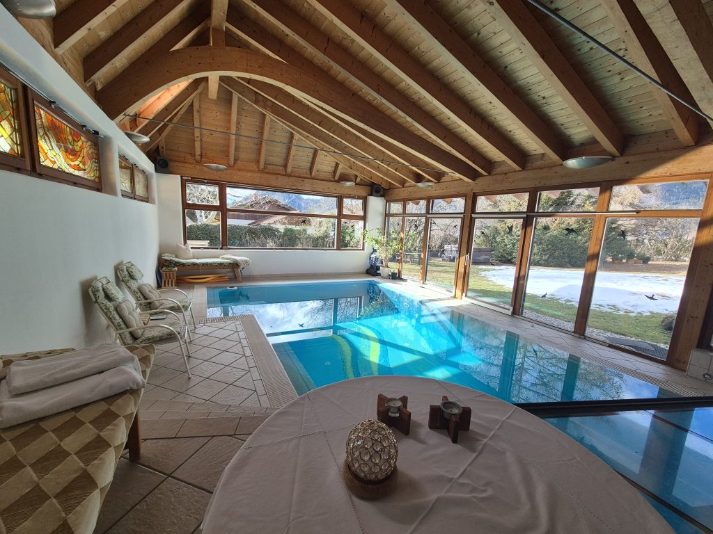 Hallenbad mit Blick in den Garten, vorne ein gedeckter Tisch