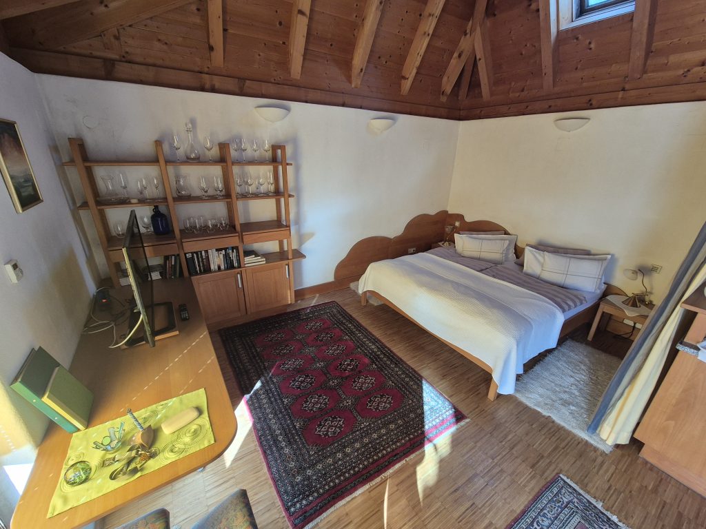 Schlafbereich im Studio mit Doppelbett unter dem Holz-Dachstuhl